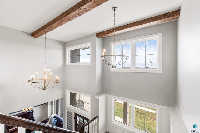 stairway with a notable chandelier, beamed ceiling, and plenty of natural light