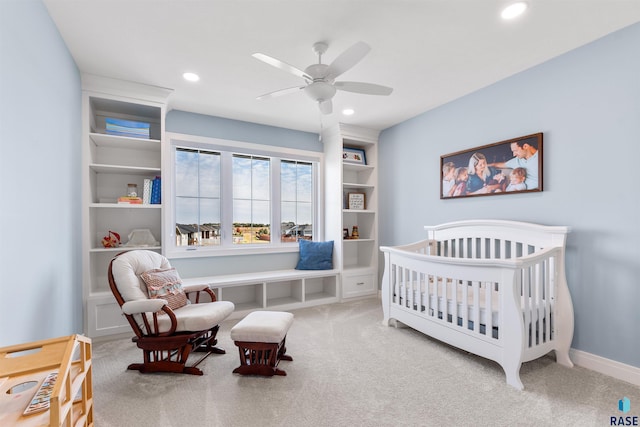 bedroom featuring a nursery area, carpet floors, and ceiling fan