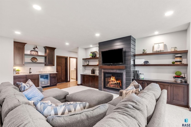 living room with wine cooler, light hardwood / wood-style flooring, wet bar, and a large fireplace