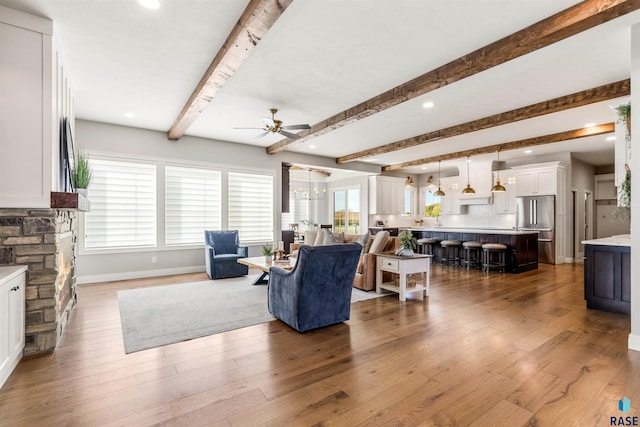 living room with beamed ceiling, wood-type flooring, and ceiling fan