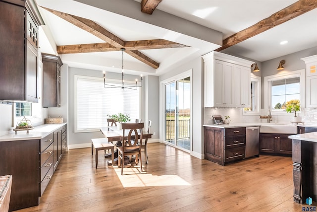 kitchen with beam ceiling, a wealth of natural light, backsplash, and light hardwood / wood-style floors