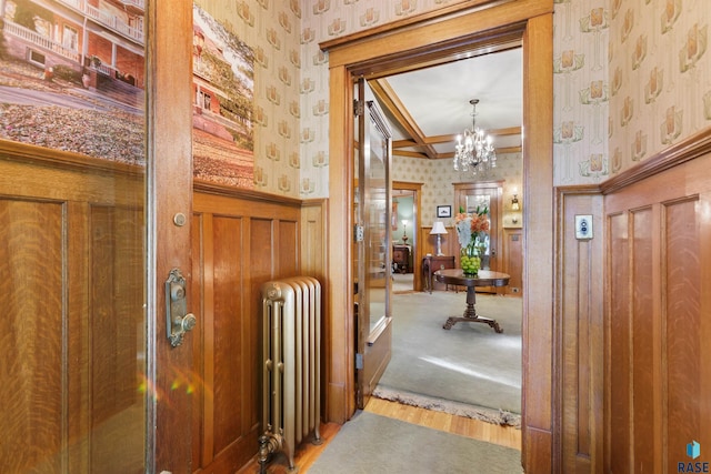 hall with wood-type flooring, an inviting chandelier, and radiator