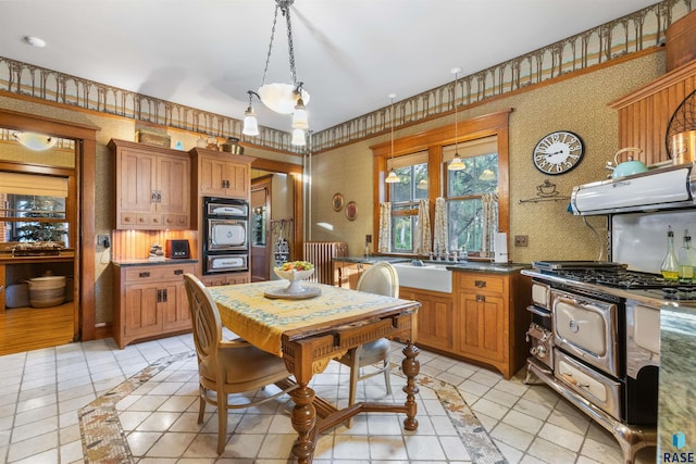 kitchen with radiator heating unit, pendant lighting, black oven, and light tile patterned floors