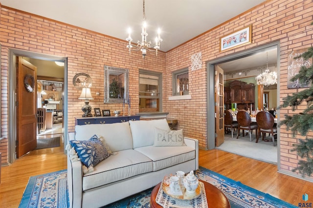 living room featuring brick wall, hardwood / wood-style floors, and an inviting chandelier