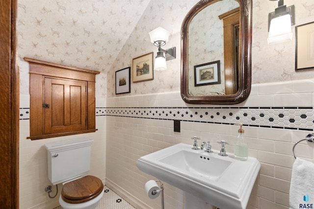 bathroom with toilet, tile walls, vaulted ceiling, and tile patterned flooring