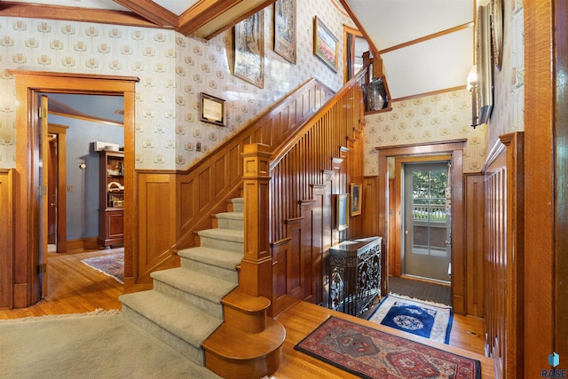 staircase with beam ceiling, hardwood / wood-style flooring, and ornamental molding