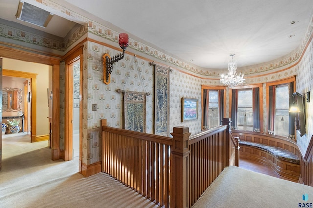 hallway with a chandelier and light colored carpet