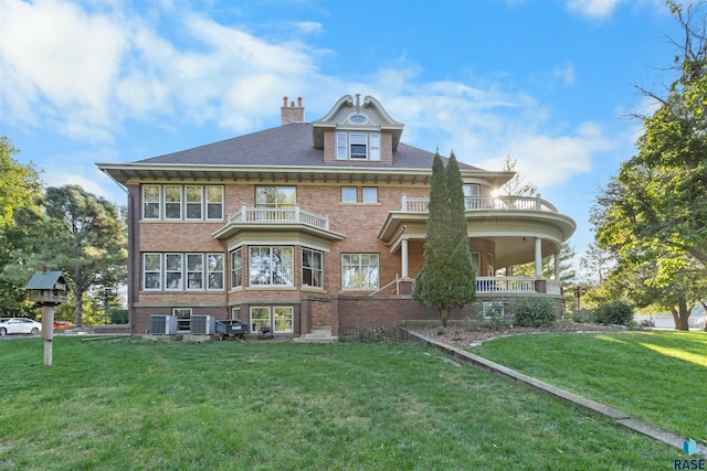 view of front of home with a front yard, central AC unit, and a balcony