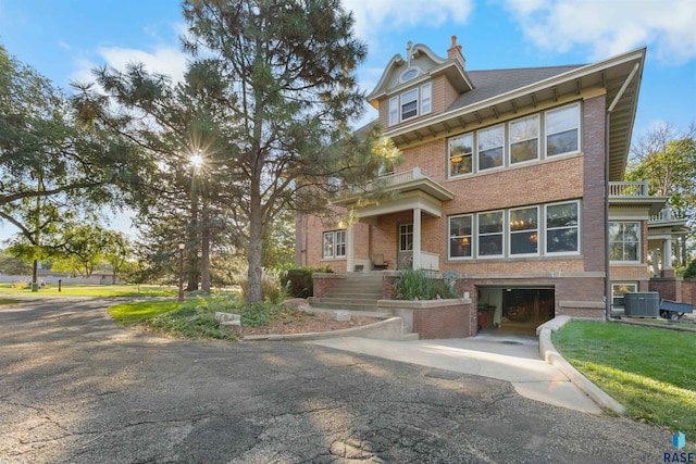 view of front of home featuring cooling unit, a garage, and a balcony