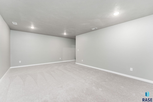 spare room featuring a textured ceiling and light colored carpet