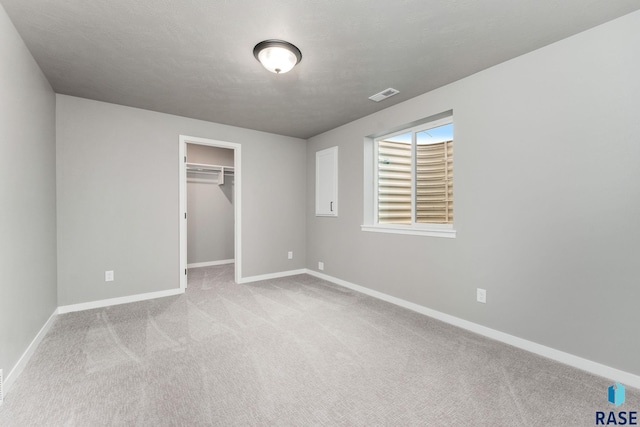 unfurnished bedroom with light colored carpet, a closet, and a walk in closet