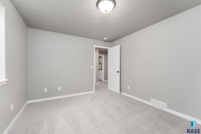 unfurnished room with a textured ceiling and light colored carpet