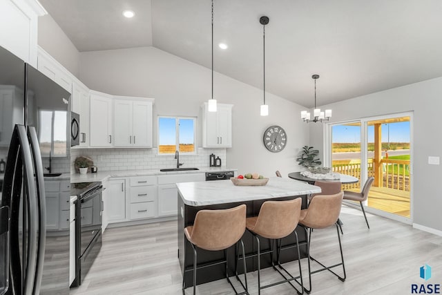 kitchen featuring a kitchen island, sink, black appliances, pendant lighting, and white cabinets