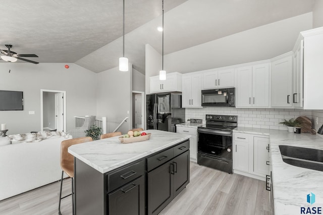 kitchen featuring black appliances, white cabinetry, decorative light fixtures, and a center island