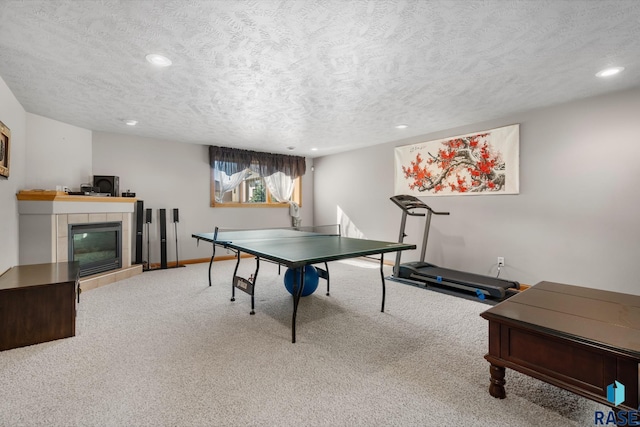 playroom featuring a textured ceiling, a tiled fireplace, and carpet floors