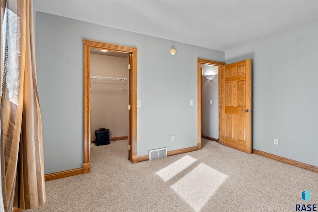 unfurnished bedroom featuring a spacious closet, light carpet, and a closet