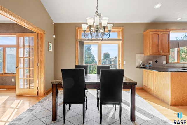 dining space with light hardwood / wood-style floors, a chandelier, and vaulted ceiling