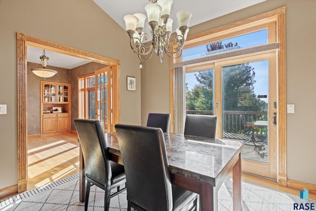 dining space featuring lofted ceiling, an inviting chandelier, and light wood-type flooring