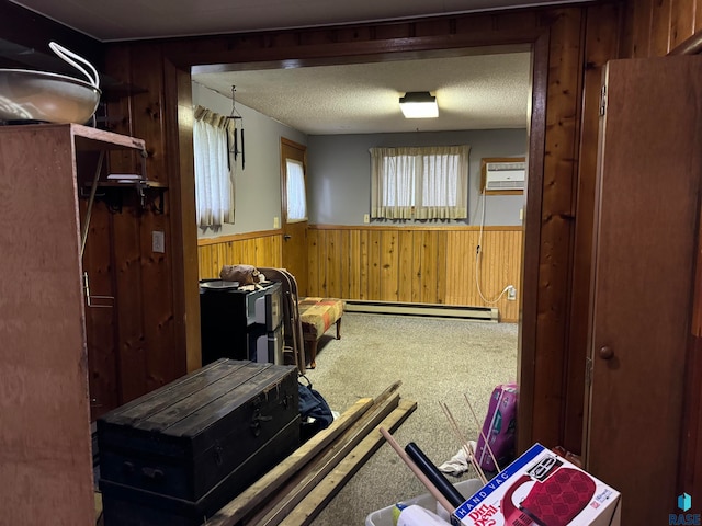 misc room with a wall mounted AC, carpet flooring, a baseboard radiator, a textured ceiling, and wood walls