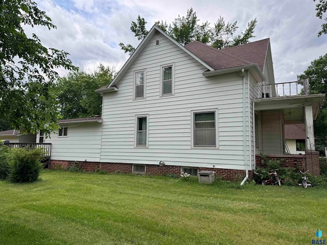 back of house with a lawn and a balcony