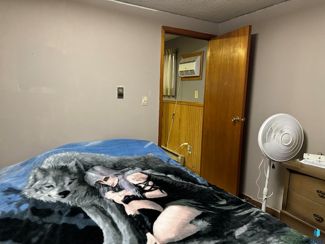 bedroom with an AC wall unit and a textured ceiling