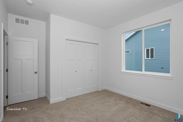 unfurnished bedroom featuring light carpet and a closet