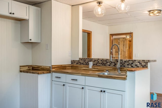 interior space featuring wood counters, tasteful backsplash, and white cabinetry