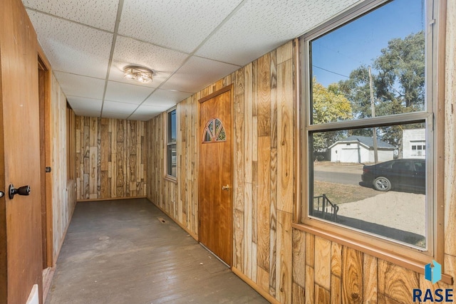 hall featuring a paneled ceiling, wood walls, and hardwood / wood-style floors