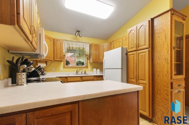 kitchen featuring white appliances, vaulted ceiling, kitchen peninsula, and sink