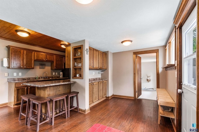 kitchen with a kitchen bar, wood ceiling, sink, and dark hardwood / wood-style flooring