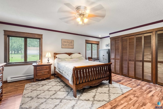 bedroom with baseboard heating, hardwood / wood-style floors, a textured ceiling, and ceiling fan