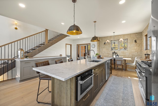 kitchen with a spacious island, sink, a kitchen bar, pendant lighting, and appliances with stainless steel finishes