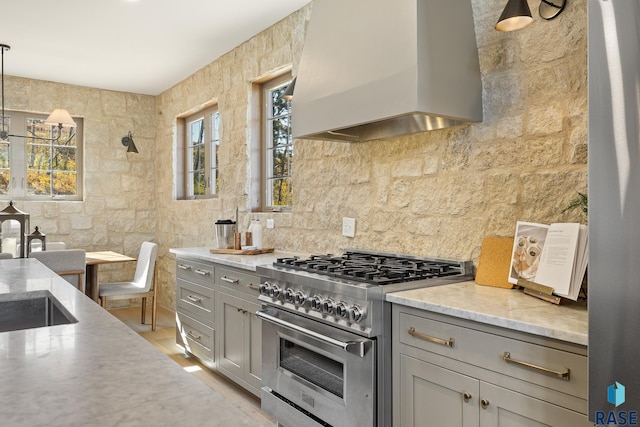 kitchen with custom range hood, decorative light fixtures, high end stove, and gray cabinetry