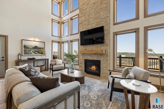 living room with a stone fireplace, a high ceiling, and light hardwood / wood-style floors