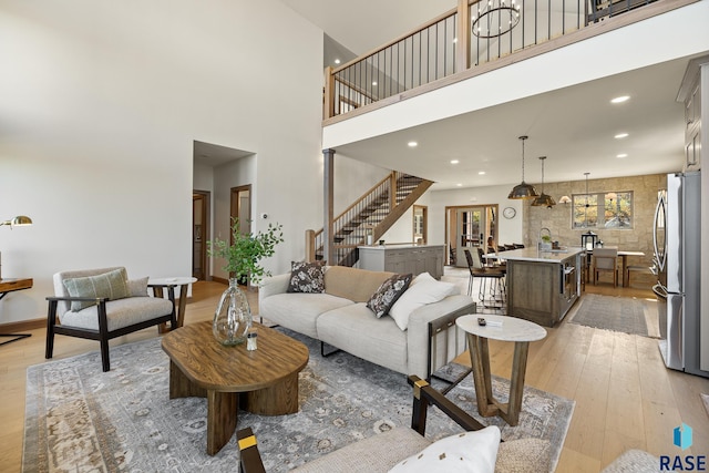 living room featuring light hardwood / wood-style floors, sink, and a towering ceiling