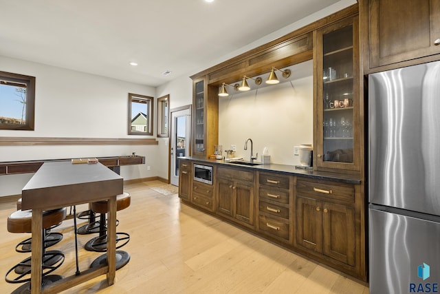 bar with appliances with stainless steel finishes, light hardwood / wood-style flooring, a healthy amount of sunlight, and sink