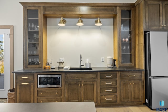 bar with sink, stainless steel appliances, and light wood-type flooring