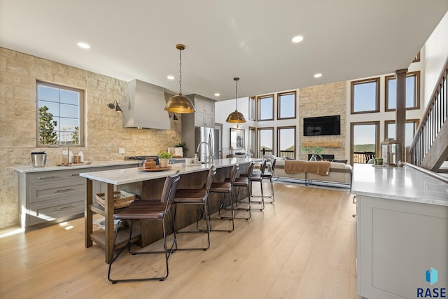 kitchen with gray cabinetry, a large island, pendant lighting, a fireplace, and light hardwood / wood-style floors