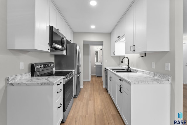 kitchen with light hardwood / wood-style floors, stainless steel appliances, sink, and white cabinets