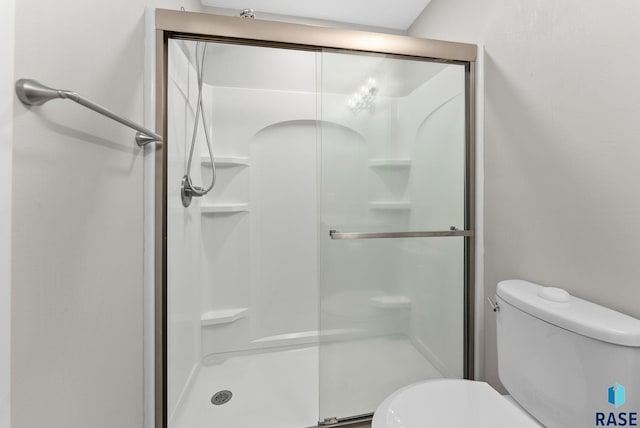 bathroom with toilet and a shower with door