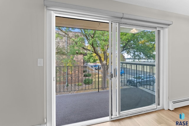 entryway with a baseboard heating unit, light wood-type flooring, and a healthy amount of sunlight