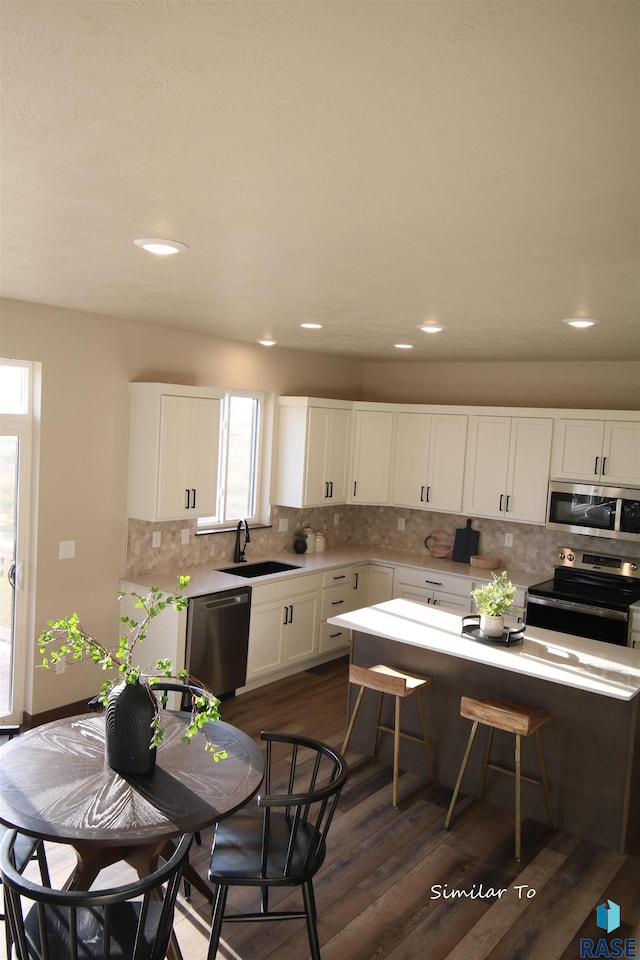 kitchen featuring a wealth of natural light, white cabinets, stainless steel appliances, sink, and a kitchen breakfast bar