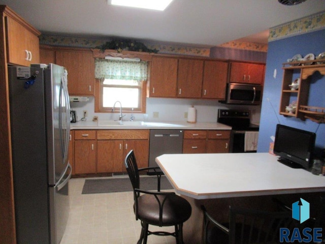 kitchen with kitchen peninsula, stainless steel appliances, sink, and a kitchen bar