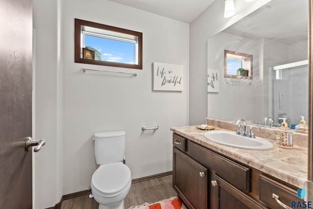 bathroom featuring vanity, hardwood / wood-style floors, toilet, and a shower with door