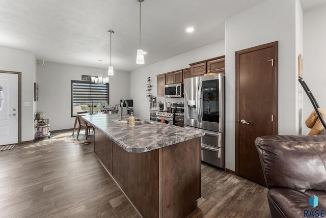 kitchen with sink, stainless steel appliances, dark hardwood / wood-style floors, decorative light fixtures, and a center island with sink