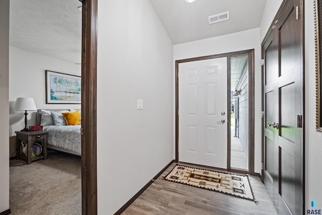 foyer entrance featuring light hardwood / wood-style floors and a textured ceiling