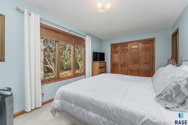 bedroom with a closet, a textured ceiling, and light colored carpet
