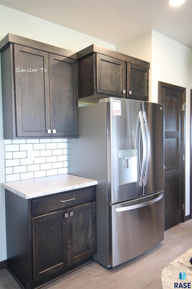 kitchen featuring backsplash, stainless steel refrigerator with ice dispenser, light hardwood / wood-style flooring, and dark brown cabinetry