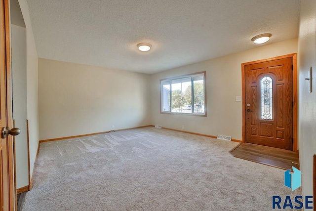 entryway featuring light colored carpet and a textured ceiling