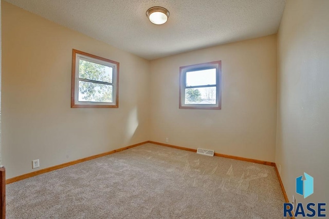 carpeted empty room with a textured ceiling